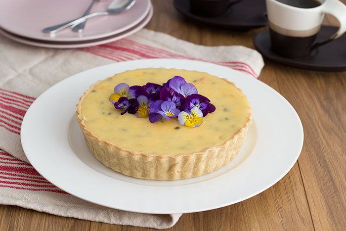 Passion fruit tart decorated with edible pansies