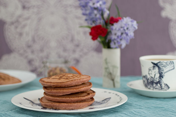 Rose pancakes stack. Flowers and tea in the background
