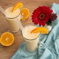 Morir Sonando drink, two glasses decorated with pieces of oranges, a cut orange and a flower